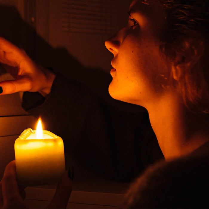 Woman holding candle near electrical panel during power outage loadshedding