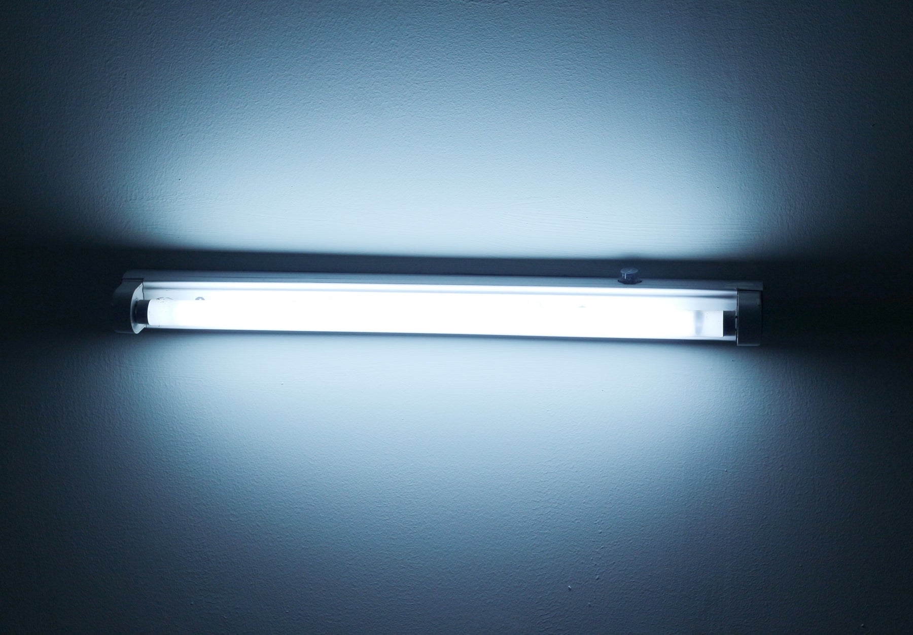Bright fluorescent or LED tube light fixture mounted on a plain wall for indoor lighting