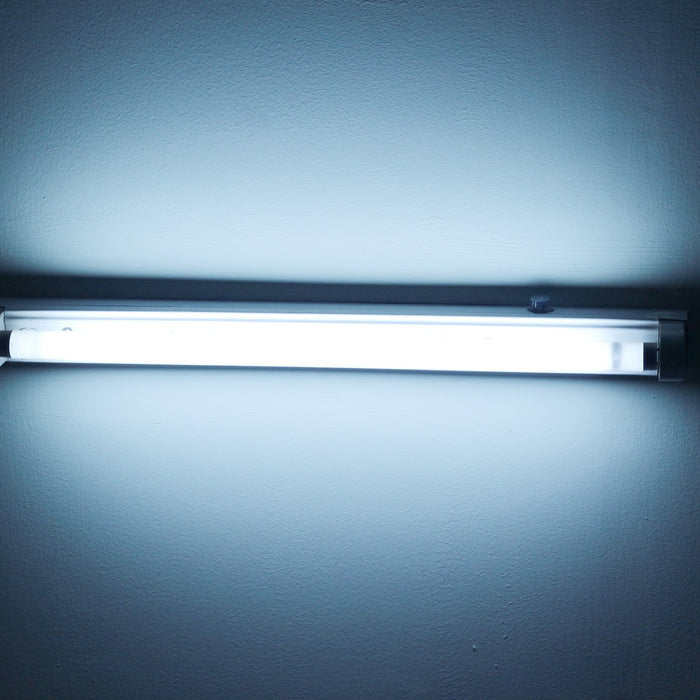 Bright fluorescent or LED tube light fixture mounted on a plain wall for indoor lighting